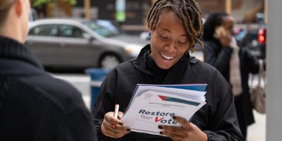 Person with a clipboard that says Restore Your Vote